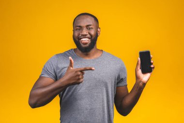 Sıradan giyinmiş, boş ekran cep telefonuna işaret eden gülümseyen Afro-Amerikan bir adamın portresi..