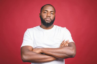 Ciddi Afro-Amerikan göz kamaştırıcı, modaya uygun, çekici, hayalperest, kameraya gelişigüzel bakan, kırmızı arka planda izole edilmiş bir adamın portresi..