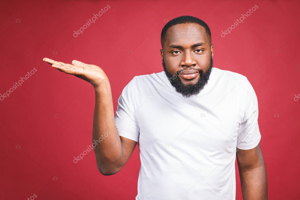 Closeup portrait of dumb clueless young african man, arms out asking why what's the problem who cares so what, I don't know. Isolated on red background. Negative human emotion facial expression feelings