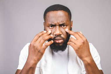 Banyodaki genç Afrikalı Amerikalı adam gri arka planda tek başına dikiliyor. Parmaklarımla gözlerimi açmaya çalışıyorum, uykum geldi ve sabah yorgunluğu çekiyorum..