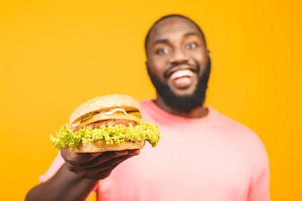 Sarı Arka Planda Izole Edilmiş Hamburger Yiyen Afrikalı Genç Bir — Stok fotoğraf