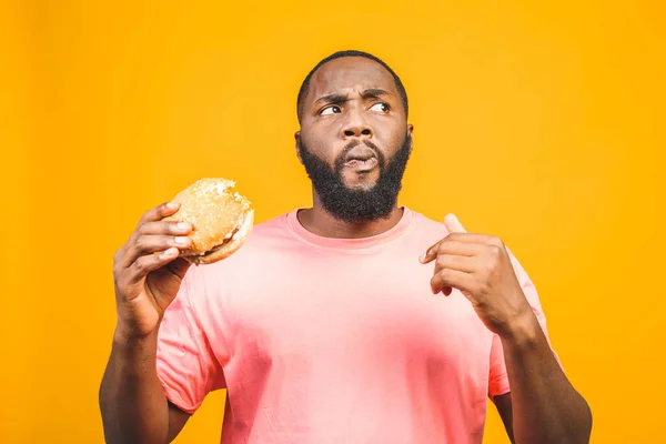 Joven Afroamericano Comiendo Hamburguesa Aislada Sobre Fondo Amarillo —  Fotos de Stock