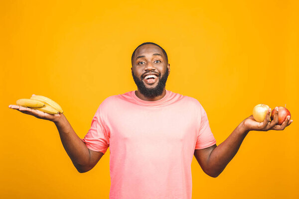 Diet concept. Healthy african american black man holding fruits isolated against yellow background.