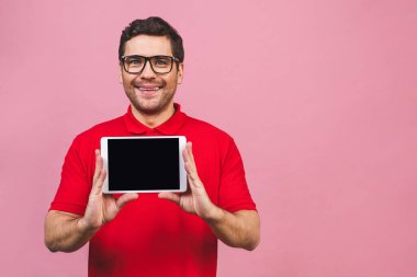 Boş ekran tabletine bağlı neşeli genç adam pembe arka planda izole edilmiş.. 