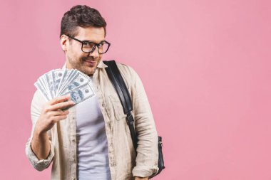 Şok olmuş gözlüklü öğrenci pembe arka planda izole edilmiş sırt çantası takıyor. Lise üniversite kolejinde eğitim. Nakit para, dolar banknotlar.. 