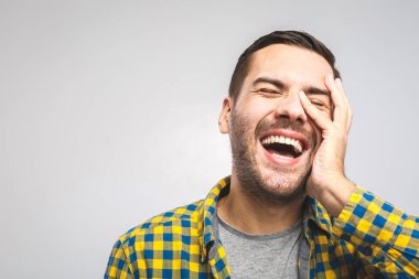 Mutlu genç adam. Sıradan gömlekli yakışıklı bir gencin portresi. Kollarını kavuşturup gülümsüyor ve beyaz arka planda duruyor.