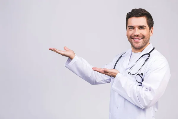 若い笑みを浮かべて医師の男性は 医学の専門家の白い背景に隔離された手の中に何かを保持 指を指す — ストック写真