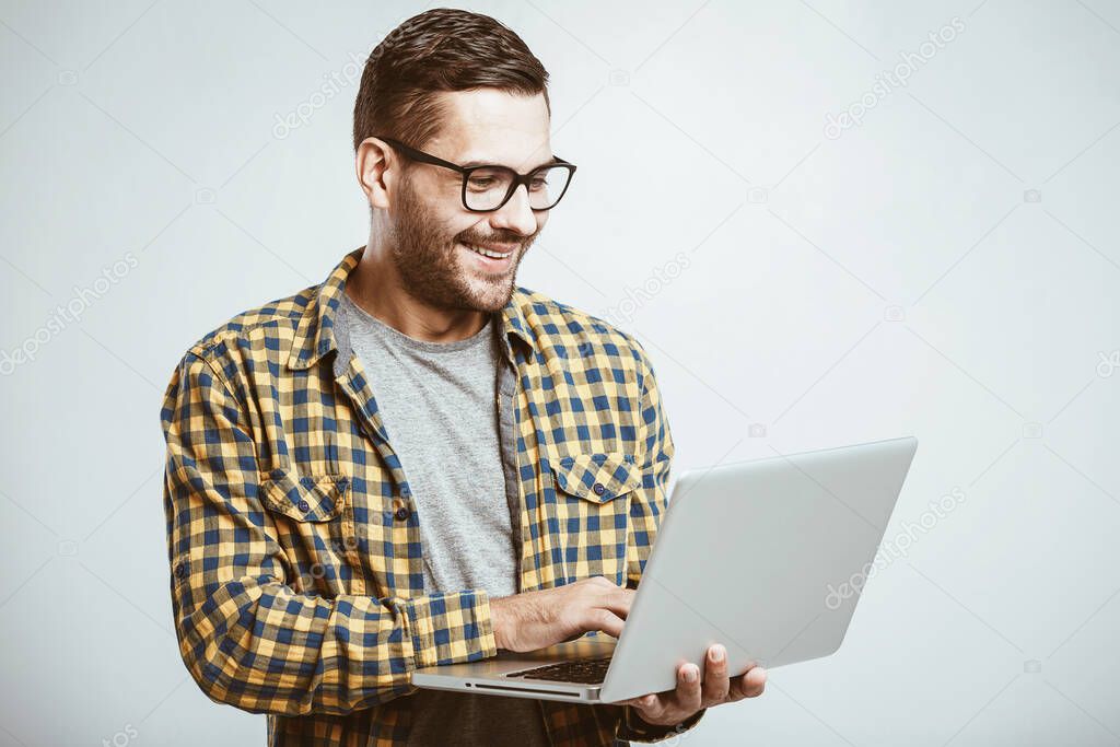 Confident business expert. Confident young handsome man in shirt holding laptop and smiling while standing against white background 