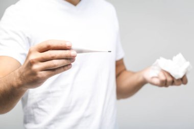 Adam üşütmüş, grip olmuş, burnu akıyor. Sağlık ve tıbbi konsept beyazda izole edildi. Sıcaklığı kontrol ediyorum. Yakın plan.