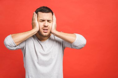 Baş ağrısı çeken genç bir adam, kafasına dokunuyor, üstünkörü giyinmiş, kırmızı arka planda soyutlanmış. Sağlık hizmetleri kavramı.