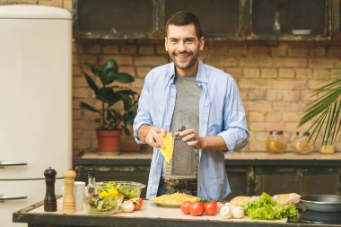 Adam güneşli bir günde ev mutfağında lezzetli ve sağlıklı yemekler hazırlıyor.. 