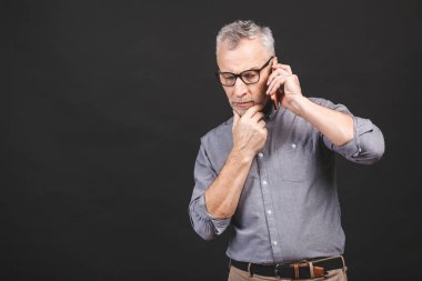 Ciddi iş kıdemli yetişkin adam siyah arka planda izole akıllı telefon jesti kullanarak resmi giyim. 