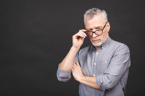 Portrait of a mature businessman wearing glasses isolated against black background. Happy senior man looking at camera with copy space. Close up face of happy successful business man. 