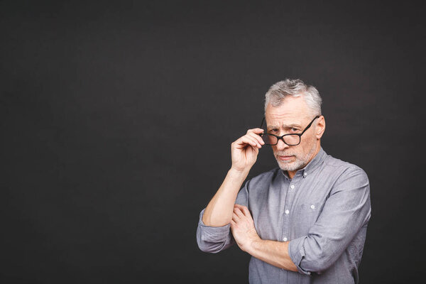 Portrait of a mature businessman wearing glasses isolated against black background. Happy senior man looking at camera with copy space. Close up face of happy successful business man. 