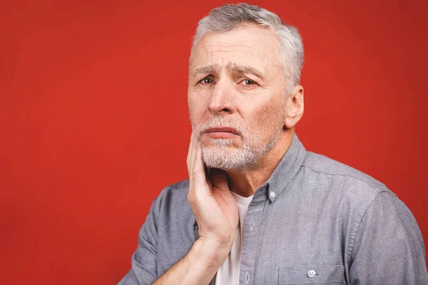 高齢者男苦しみから歯痛に上の赤い背景 — ストック写真