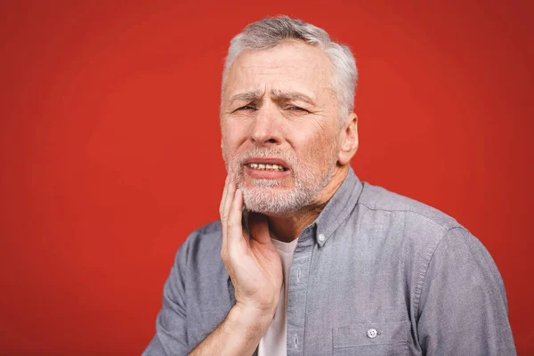 赤い背景に歯痛を患っている高齢者のクローズアップポートレート — ストック写真