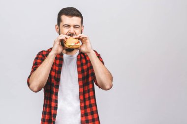 Hamburger tutan genç bir adam. Öğrenci fast food yiyor. Burger yararlı bir yemek değildir. Çok aç bir adam. Diyet kavramı beyaz arkaplanda izole edildi. 
