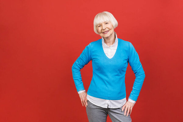Senior happy aged businesswoman wearing glasses. Beautiful old woman looking at camera and smiling. Isolated on red background. 