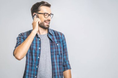 Haberler harika! Gri arka planda telefonla konuşan güler yüzlü genç bir adam. İzole edilmiş.