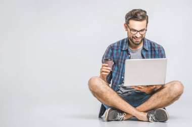 Çevrimiçi çalışma konsepti. Sıradan bir iş adamı rahat rahat internette kahve içip dizüstü bilgisayarda gezinirdi. Ev ofisindeki dizüstü bilgisayarda oturup daktilo yazan serbest çalışan.. 