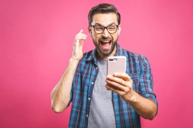 Mutlu galip! Mutlu gülümseyen genç adam kulaklıkla müzik dinliyor ve pembe arka planda dans ediyor. İzole edilmiş.