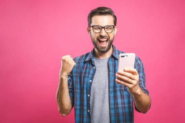 Ben bir kazananım! Akıllı telefonu tutan ve başarısını pembe arka planda kutlayan mutlu bir adam..
