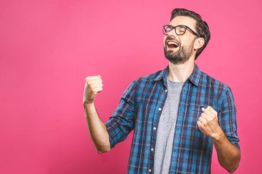 İşte bu! Mutlu galip! Mutlu genç yakışıklı adam pembe arka planda dikilirken el kol hareketi yapıyor ve ağzını açık tutuyor..