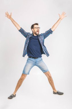 Mutlu neşeli genç adam atlıyor ve başarıyı kutluyor beyaz bir arka planda izole edilmiş.