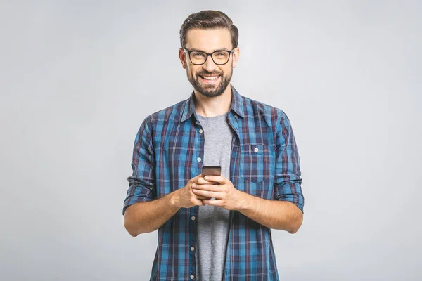 Gözlüklü genç adam gri arka planda SMS yazıyor.
