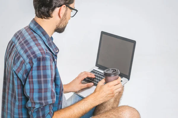 Online working concept. Casual business man relaxed working and browsing internet on laptop computer with coffee. Freelance sitting and typing on laptop keyboard at home office. Close up