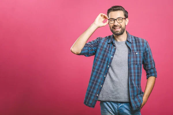 People and positive emotions concept. Delighted glad bearded male with stylish hairdo, dark beard, keeps eyes shut, smiles joyfully, dressed in casual, isolated over pink background