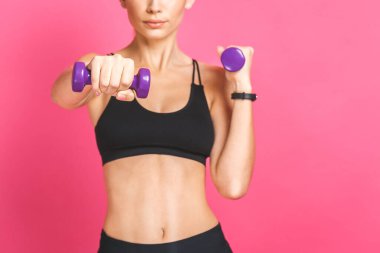 Sportif kadın egzersizleri halterlerle yapıyor. Beyaz arka planda spor giysili kadın fotoğrafı. Güç ve motivasyon. Pembe üzerine izole edilmiş..
