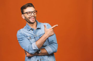 Yakışıklı, gülümseyen sakallı adam turuncu arka planı işaret ediyor..