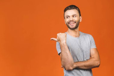 Yakışıklı, gülümseyen sakallı adam turuncu arka planı işaret ediyor..