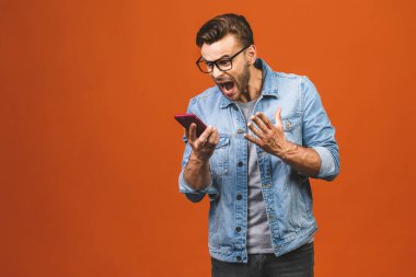 Kafkasyalı genç adam kızgın, hayal kırıklığına uğramış ve telefonuna öfkeli turuncu arka plan üzerinden müşteri hizmetlerine kızgın.. 