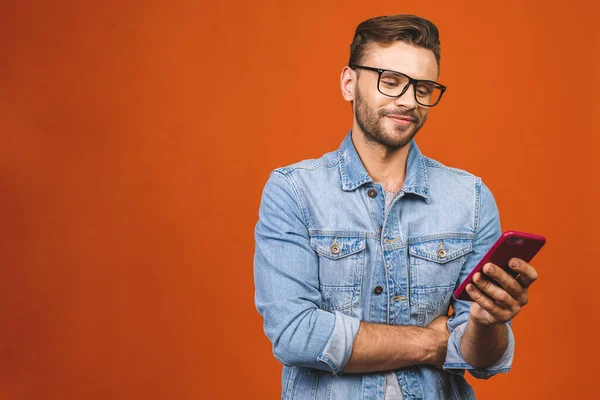 Geweldig Nieuws Gelukkig Jongeman Bril Typen Sms Geïsoleerd Tegen Oranje — Stockfoto