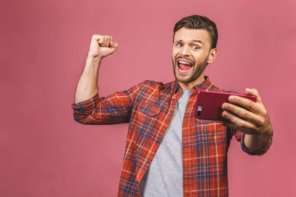 Portré Egy Izgatott Fiatalember Nézi Mobiltelefon Elszigetelt Rózsaszín Háttér Győztes — Stock Fotó