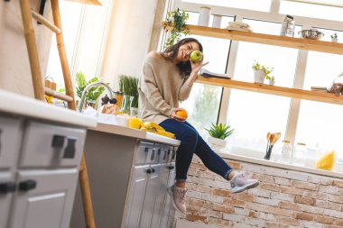 Eğleniyoruz! Genç ve güzel bir kadın mutfakta yemek pişiriyor..