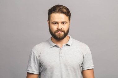 Mutlu genç adam. Gri arka planda dikilmiş gülümseyen yakışıklı genç adamın portresi.