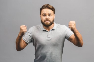 Öfkeli, öfkeli, suratında somurtkan, ağzı açık, tartışmaya ve küfretmeye hazır, saygı kazanmak isteyen, güç göstermek isteyen, gri arka planda soyutlanmış bir adam.