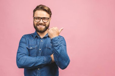 Tişörtlü mutlu sakallı adam pembe arka planda izole edilmiş bir yeri işaret ediyor..