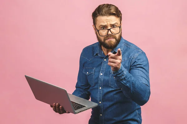 Confident business expert. Confident serious young handsome man in casual holding laptop while standing against isolated pink background.