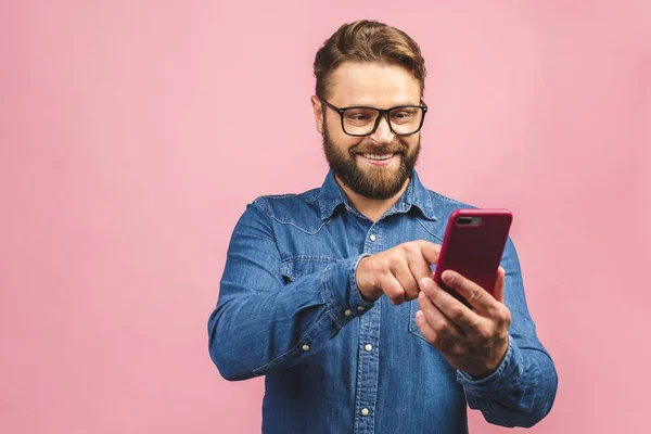 Šťastný Mladý Vousatý Muž Brýlích Psaní Sms Růžovém Pozadí — Stock fotografie