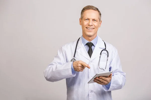 灰色の背景に隔離されたPcタブレットを使用して聴診器で明るい笑顔のシニア医師の肖像画 — ストック写真