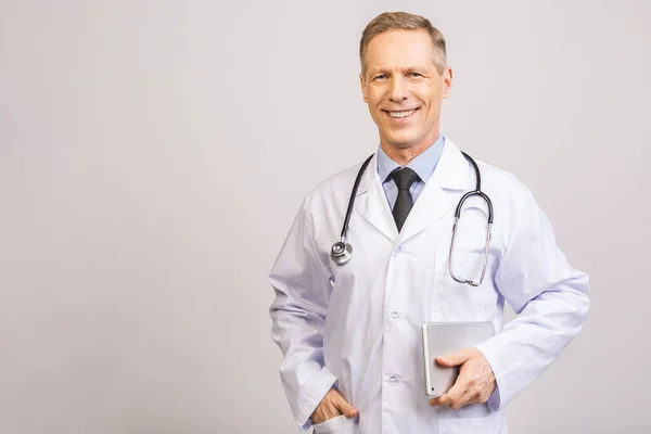 Portrait of a cheerful smiling senior medical doctor with stethoscope and pc tablet isolated on grey background.