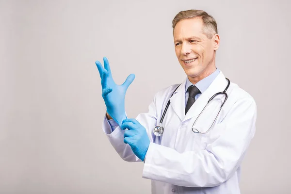 シニア医師上の滅菌手袋グレーの背景に隔離 — ストック写真
