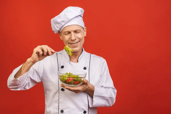 Kırmızı Duvarın Arkasında Duran Elinde Salata Tutan Yiyen Üniformalı Genç — Stok fotoğraf