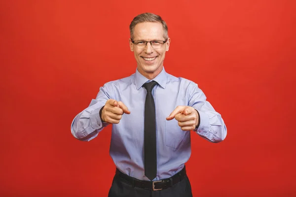 Follow me! Look here! Close up portrait of cheerful satisfied pleased qualified experienced joyful aged businessman pointing on empty blank place isolated on red background.