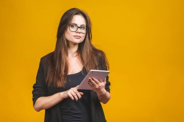 İş kadını elinde tablet bilgisayarla sarı arka planda izole edilmiş..