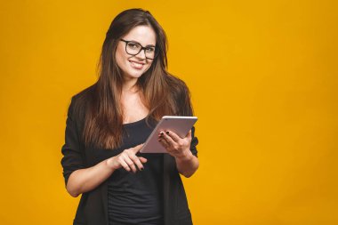 İş kadını elinde tablet bilgisayarla sarı arka planda izole edilmiş..